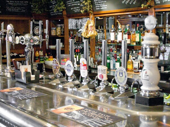 A bar with multiple beer taps and a variety of bottles in the background. - The Swans Nest Hotel (Stratford-upon-Avon)