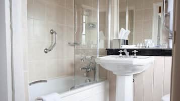 A modern bathroom with a glass-enclosed shower, a white bathtub, and a pedestal sink.