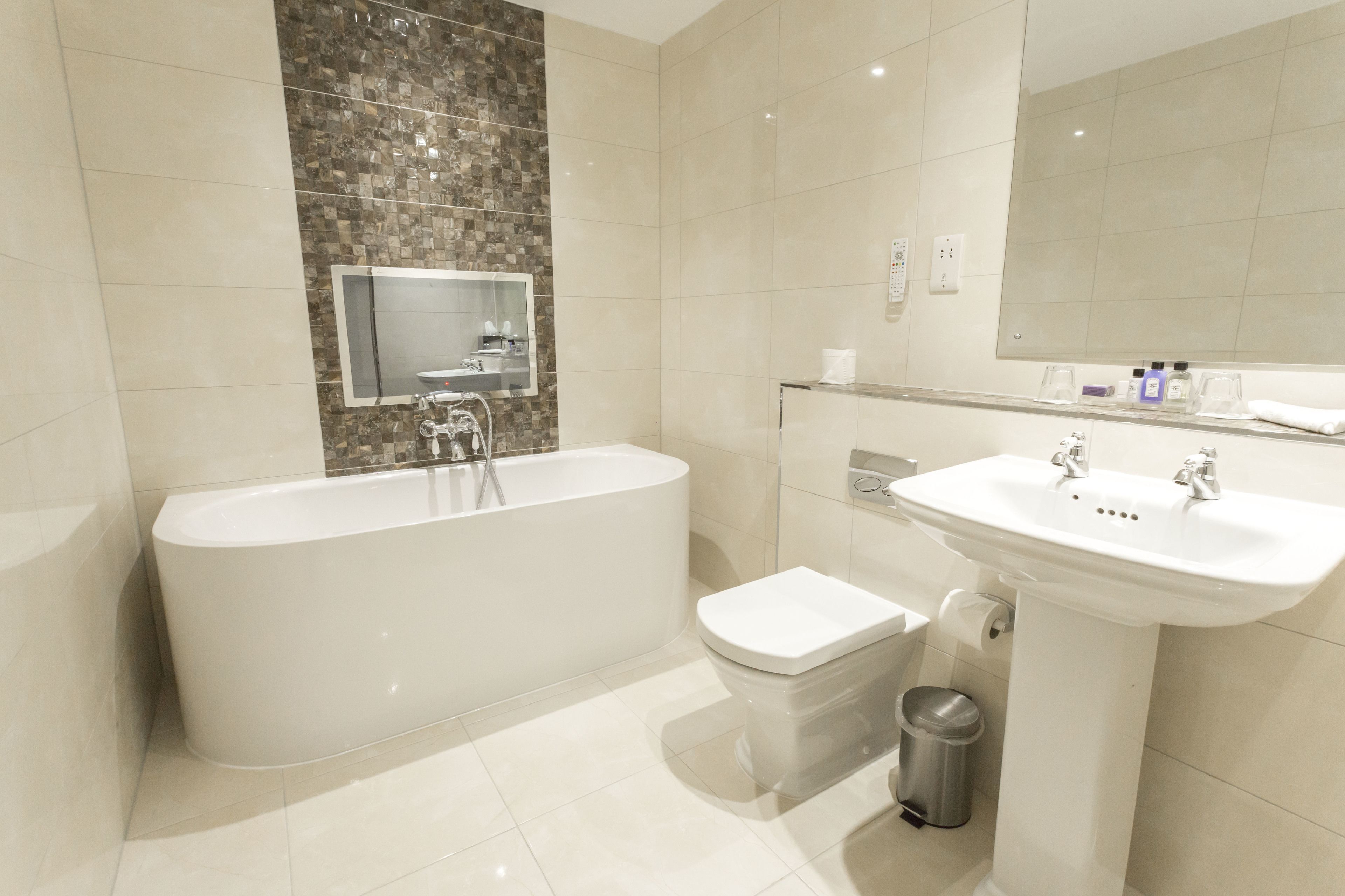 A modern bathroom with a freestanding bathtub, a pedestal sink, and a toilet.