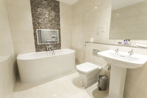 A modern bathroom with a freestanding bathtub, a pedestal sink, and a toilet.