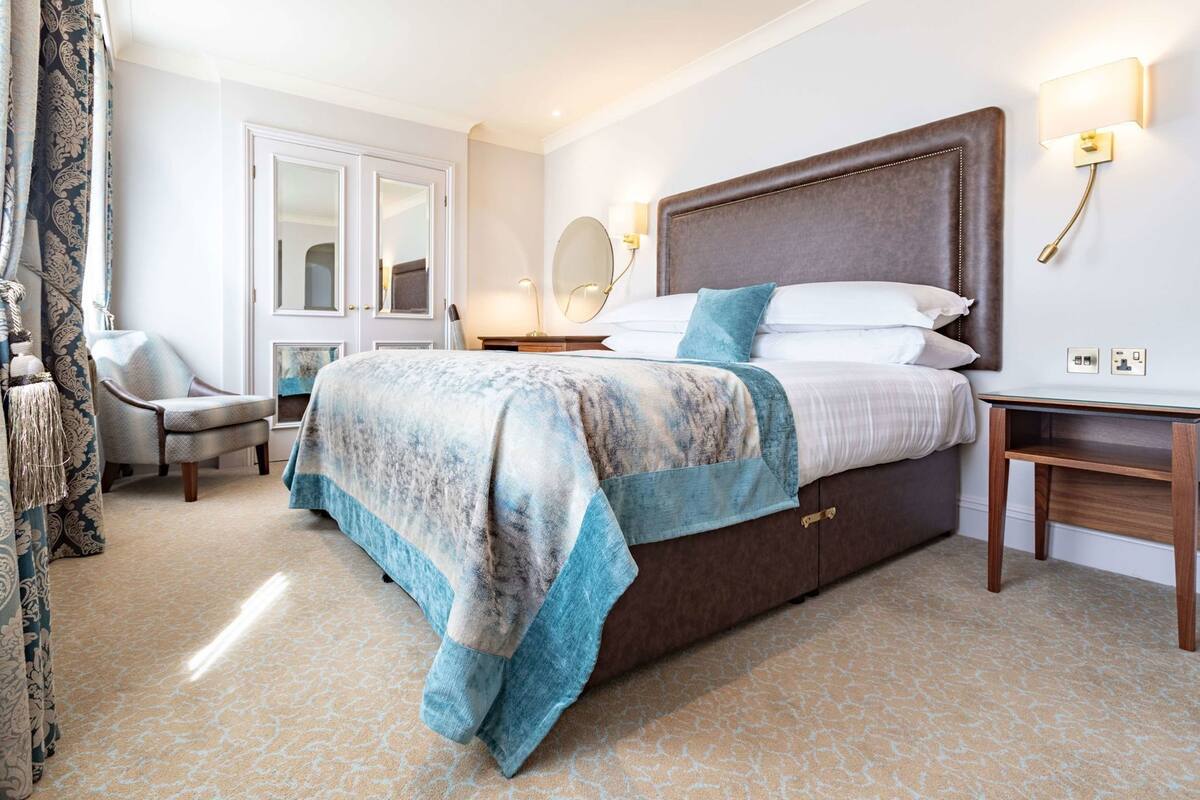 Een hotelkamer met een groot bed, een stoel, een bureau en een spiegel.