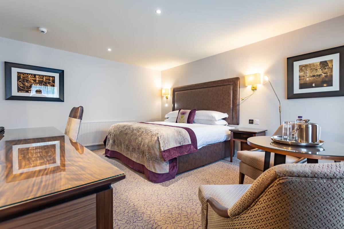 Een hotelkamer met een bed, nachtkastjes, een bureau en stoelen.