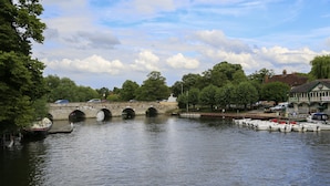 Un pont de pierre enjambe une rivière, avec des bateaux amarrés à proximité.