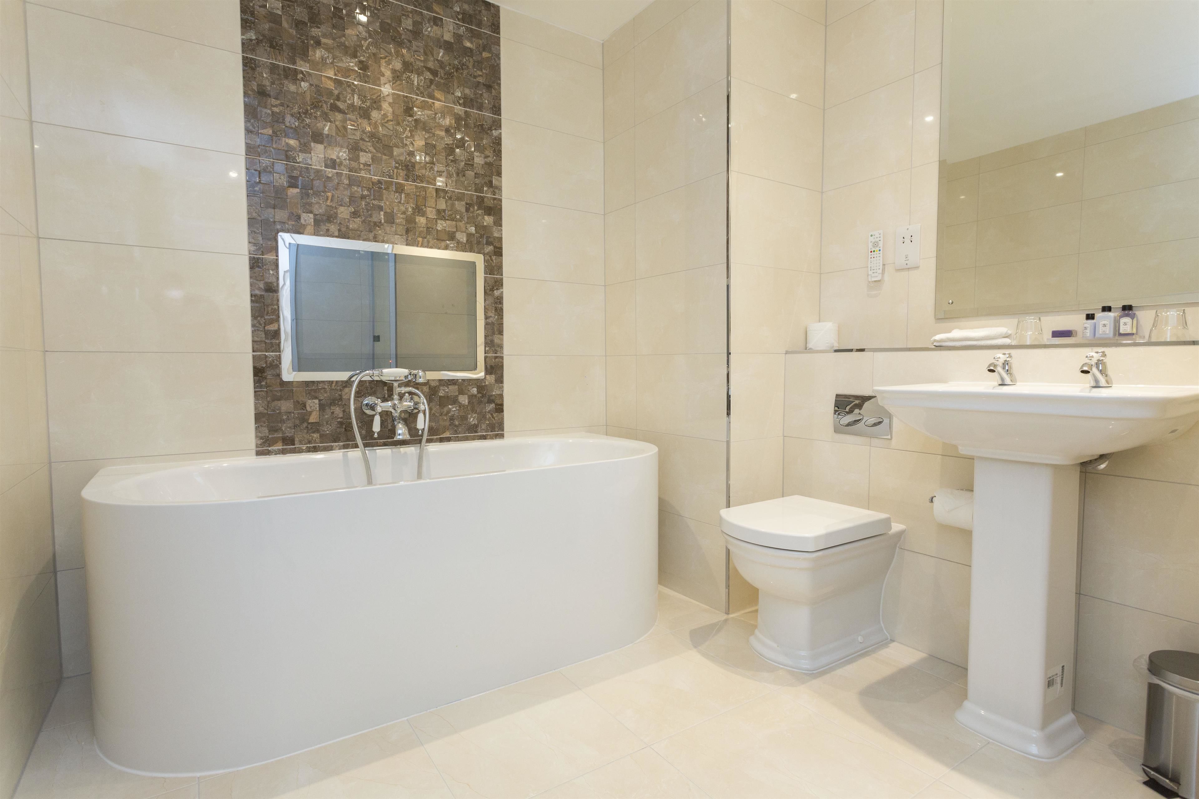 Un baño moderno con una bañera independiente, un lavamanos pedestal y un inodoro.