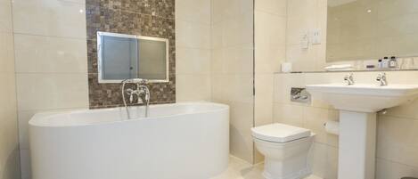 A modern bathroom with a freestanding bathtub, a pedestal sink, and a toilet.