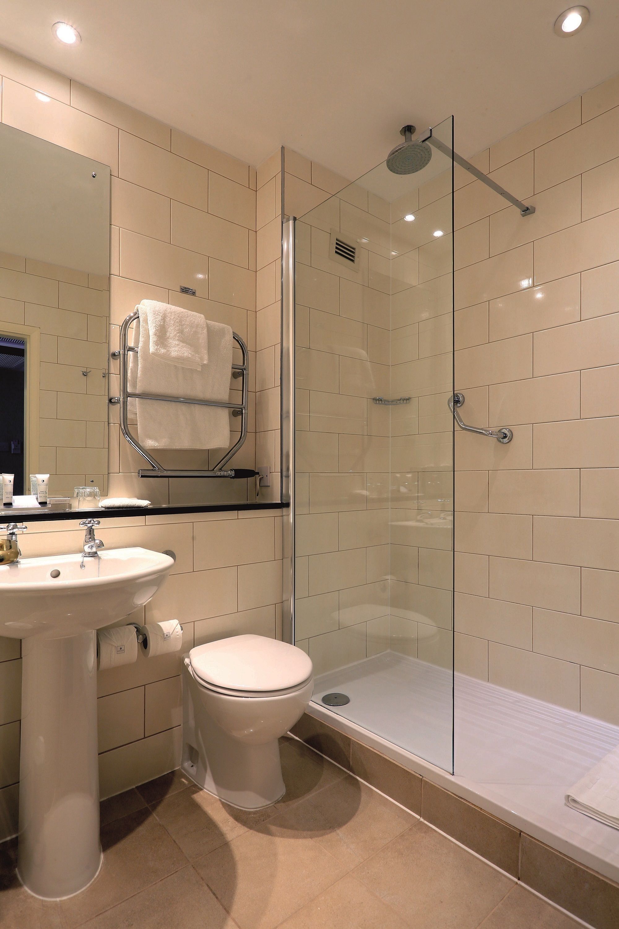 A modern bathroom with a glass-enclosed shower, a sink, and a toilet.