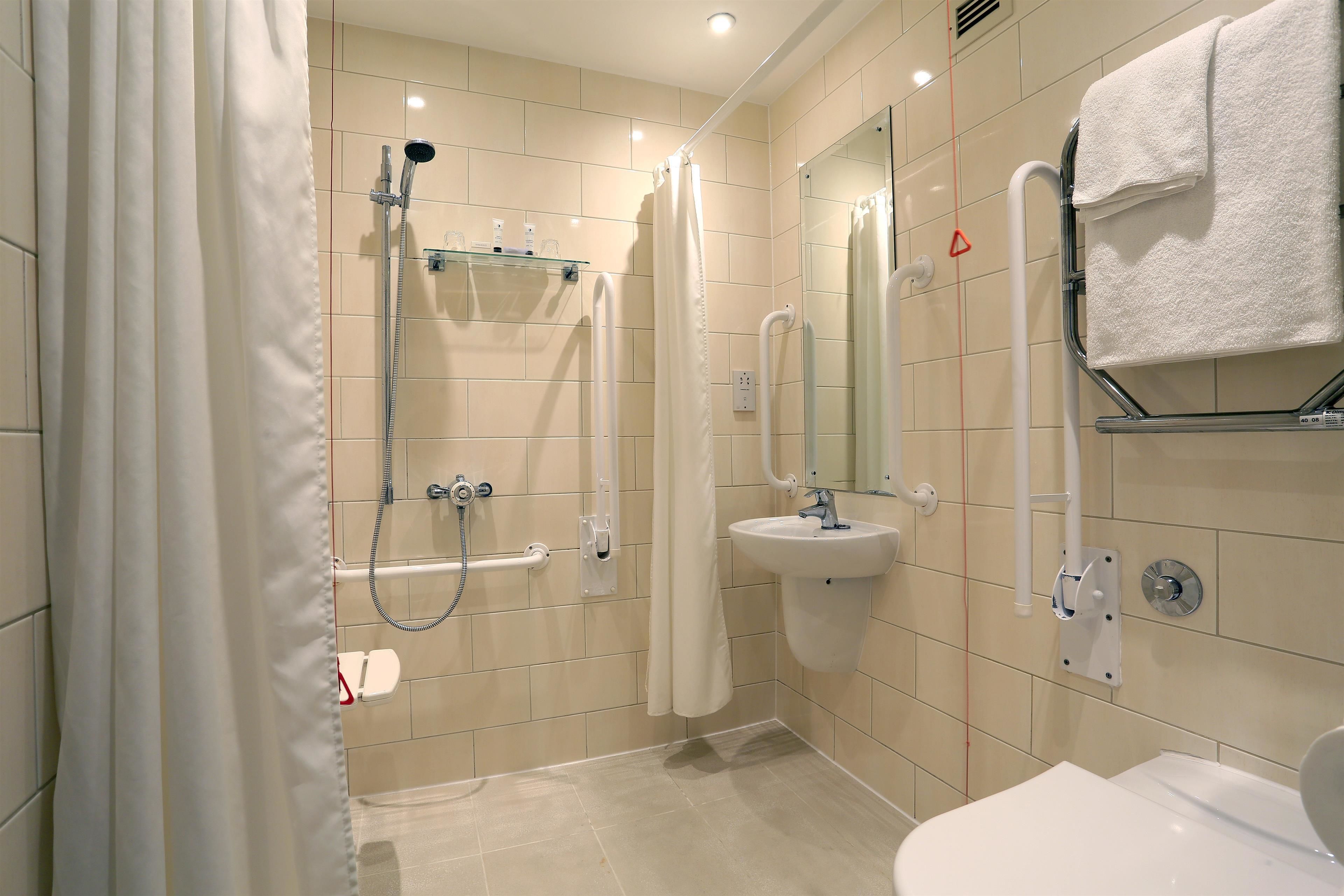 A modern bathroom with a shower, a sink, and a toilet.