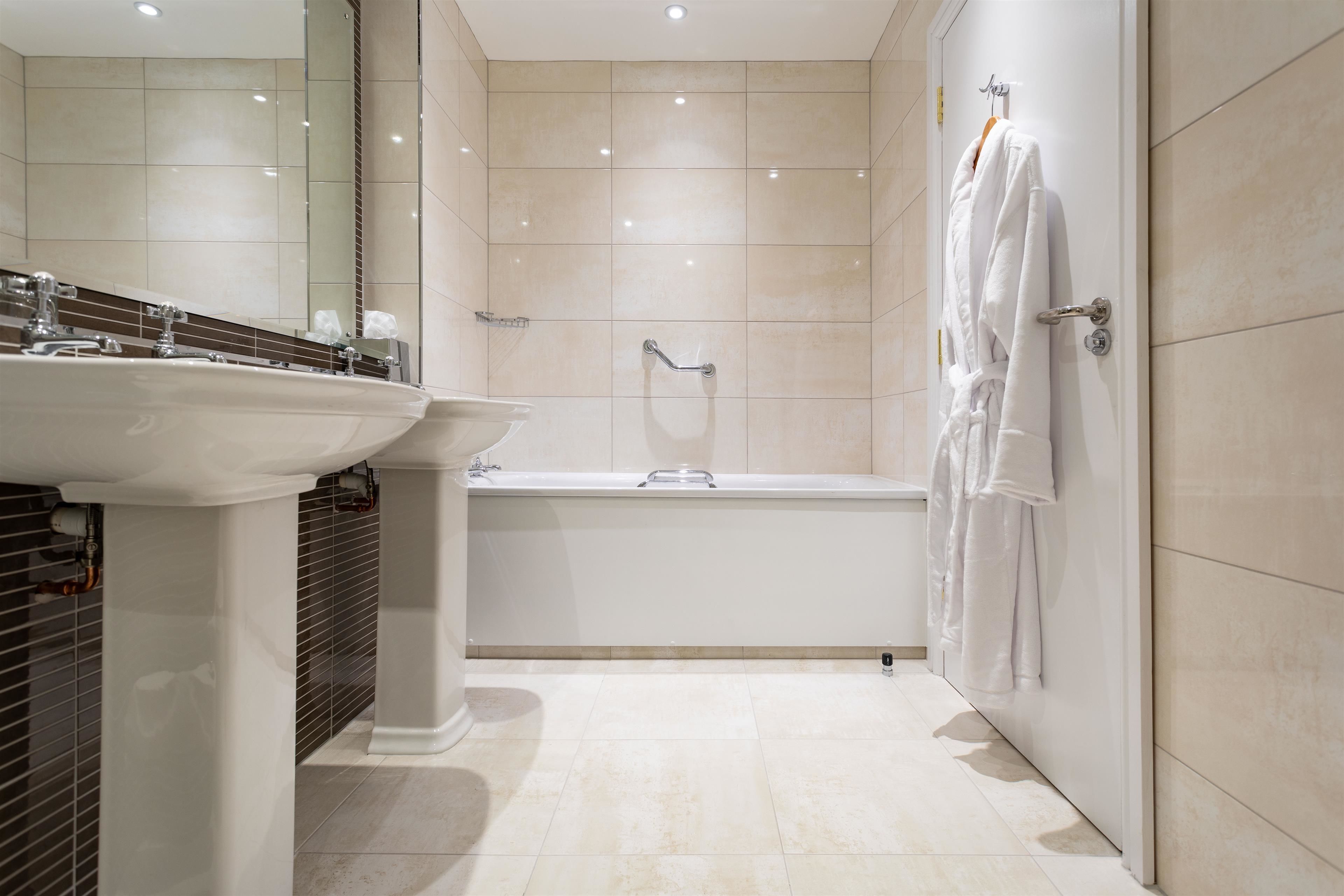 A modern bathroom with a sink, mirror, bathtub, and towel rack.
