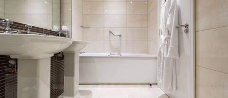 Une salle de bain moderne équipée d’un lavabo, d’un miroir, d’une baignoire et d’un porte-serviettes.