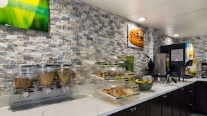 Un comptoir de petit-déjeuner avec divers aliments, un appareil à gaufres et une machine à café.