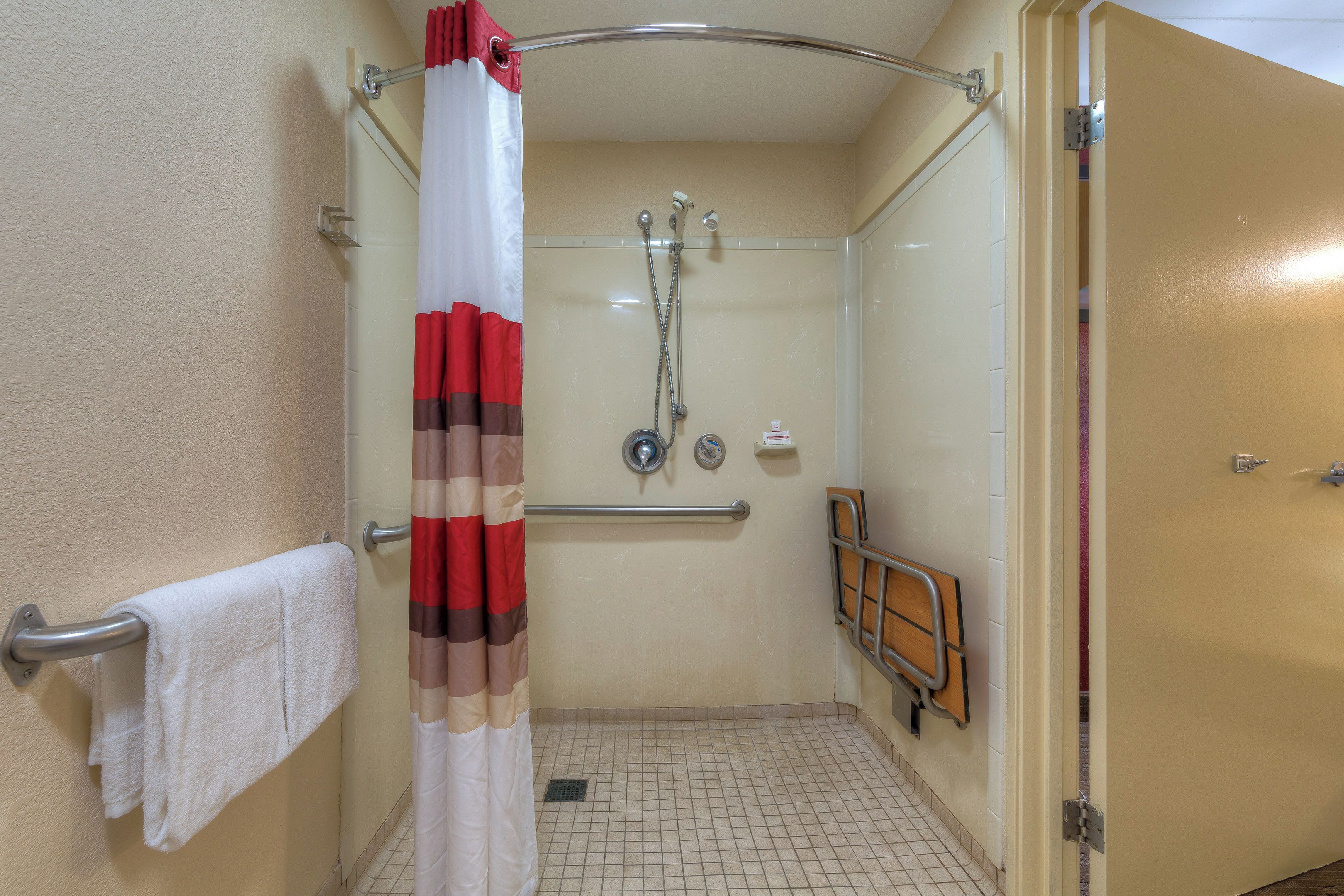 A shower area with a glass door, a towel rack, and a shower control panel.