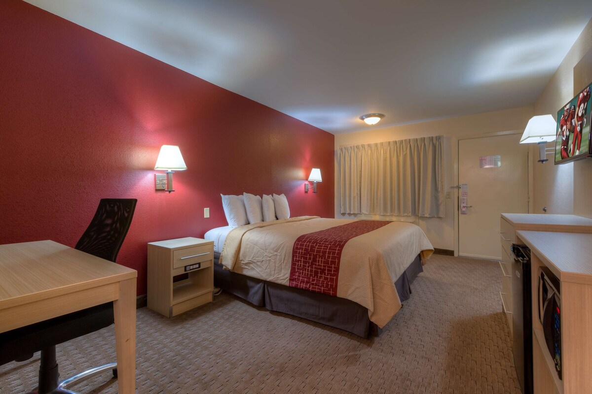 A hotel room with a bed, bedside tables, a desk, and a wardrobe.