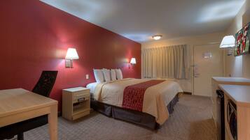 A hotel room with a bed, bedside tables, a desk, and a wardrobe.