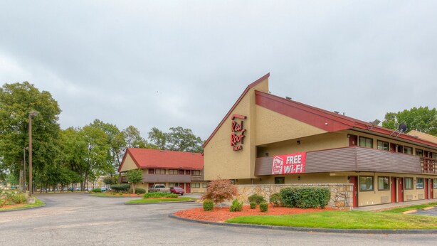 A Red Roof Inn with a red roof and beige walls, a parking lot, and surrounding greenery. - Red Roof Inn Memphis East (Memphis)