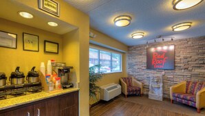 A hotel lobby with a coffee station, a fireplace, and a Red Roof Inn sign. - Red Roof Inn Memphis East (Memphis)