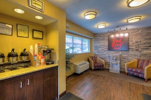 A hotel lobby with a coffee station, a fireplace, and a Red Roof Inn sign. - Red Roof Inn Memphis East (Memphis)