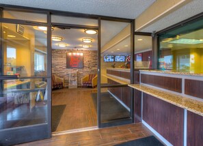 A hotel reception area with a stone wall, a Red Roof Inn sign, and a reception desk. - Red Roof Inn Memphis East (Memphis)