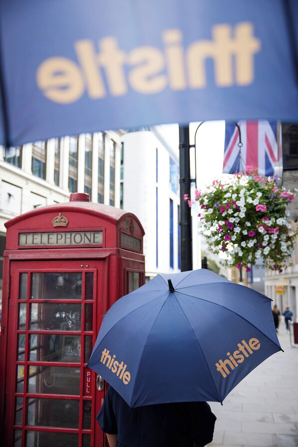 Cabina telefónica roja con bandera británica y una maceta colgante de flores.