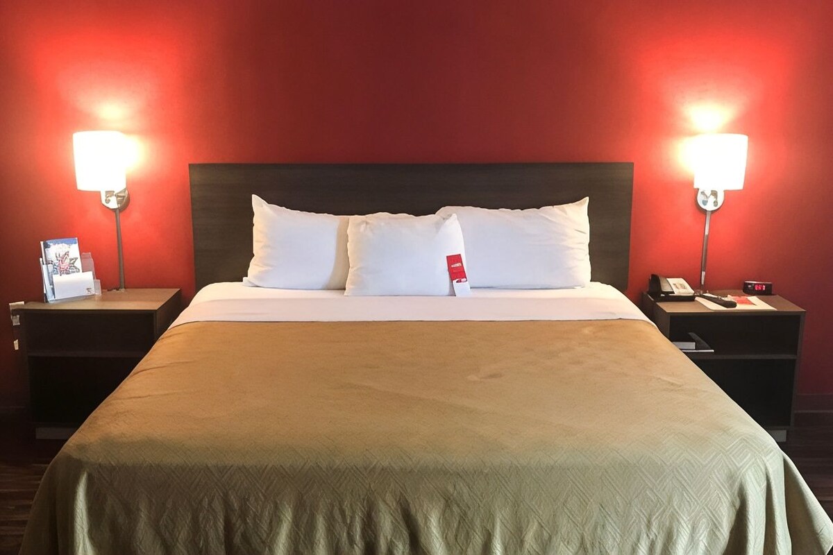 A hotel room with a large bed, two bedside tables, and two wall-mounted lamps.