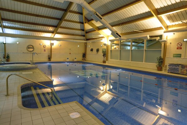 An indoor swimming pool with clear lanes, a changing room, and a sauna area.