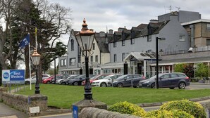 A hotel with a sign for 'Best Western Kings Manor Hotel'. There are parked cars in front, a stone wall, and a lamp post.