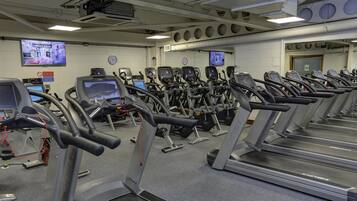Un gimnasio con cintas de correr, bicicletas estáticas y máquinas de cardio.