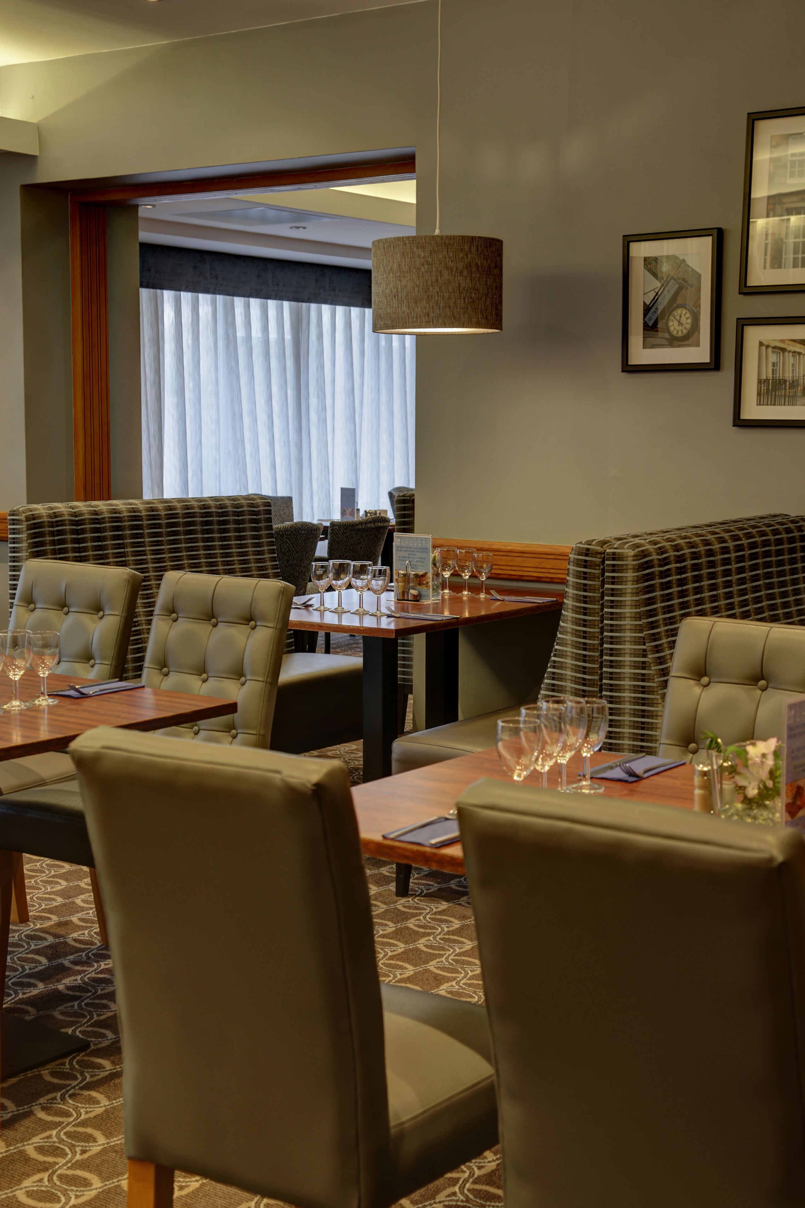 Een restaurantgedeelte van een hotel, met een grote tafel gedekt voor een maaltijd, omringd door gestoffeerde stoelen.