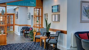 A hotel lobby with a reception desk, seating area, and a sign reading "LAUDERS IT".