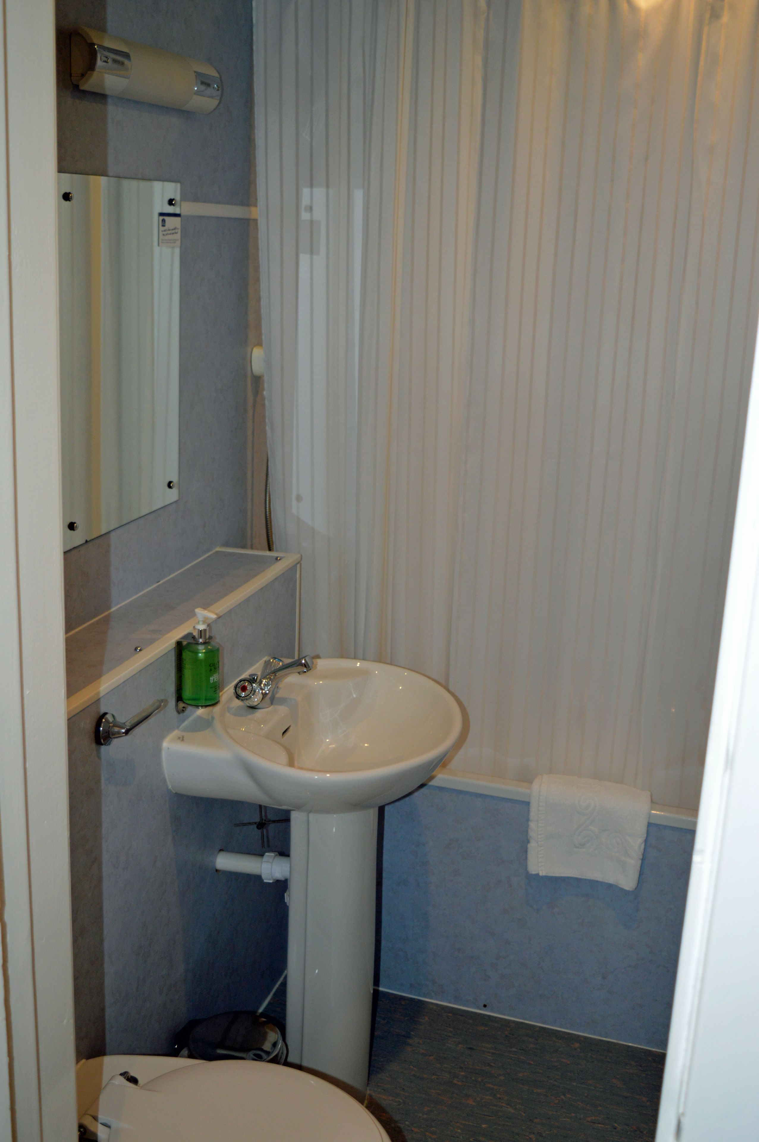 A bathroom with a sink, mirror, and towel rack.