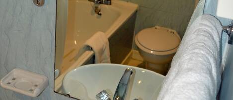 Un baño con lavamanos, espejo e inodoro.