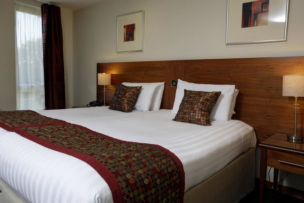 A hotel room with a large bed, two bedside tables, and a wooden headboard.