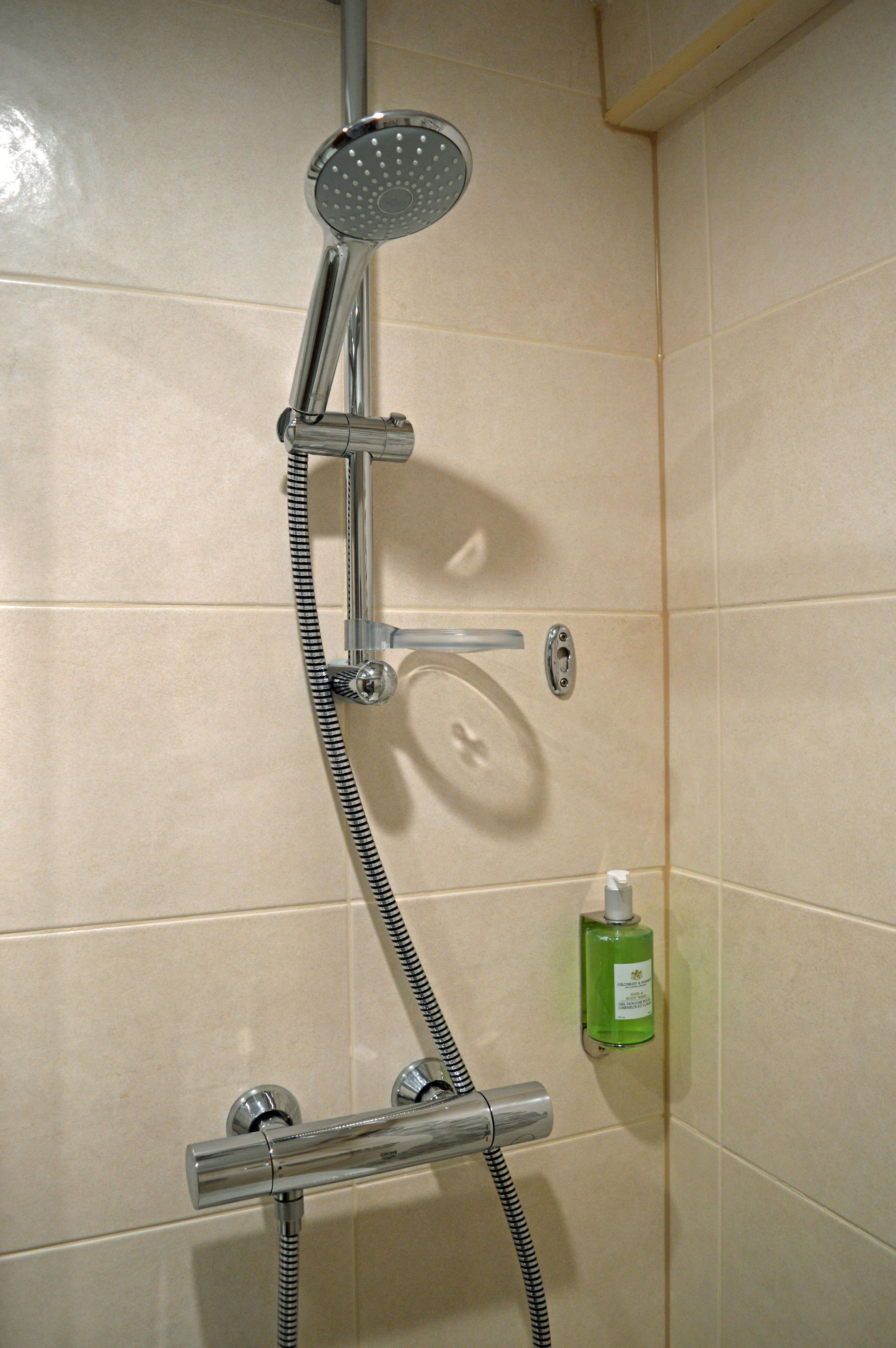 Een douche met een handdouche, een doucheaanslag en een handdoucheslang.