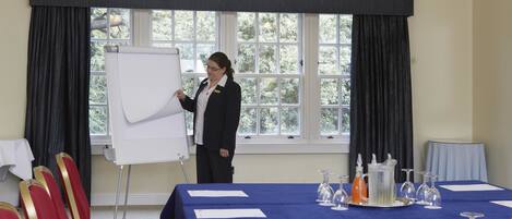 A conference room with a whiteboard, a table with name cards, and a window with curtains.