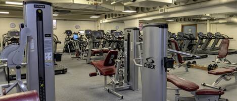 A gym with various exercise machines, including treadmills and weightlifting equipment.