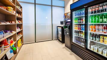 A clean, well-organized room with shelves stocked with snacks and a refrigerator filled with beverages.