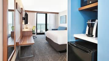 A hotel room with a bed, a desk, a chair, a television, a coffee machine, and a view of the sea.