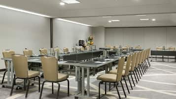 Un salón de conferencias con una larga mesa, sillas y una estación de café.