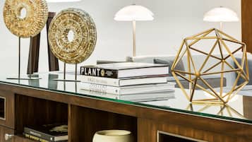 Un bureau à plateau en verre agrémenté d’objets décoratifs, de livres et d’une sculpture géométrique.