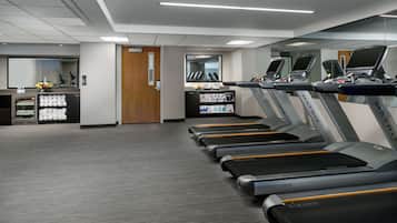 A gym with treadmills, a reception desk, and a mirror.