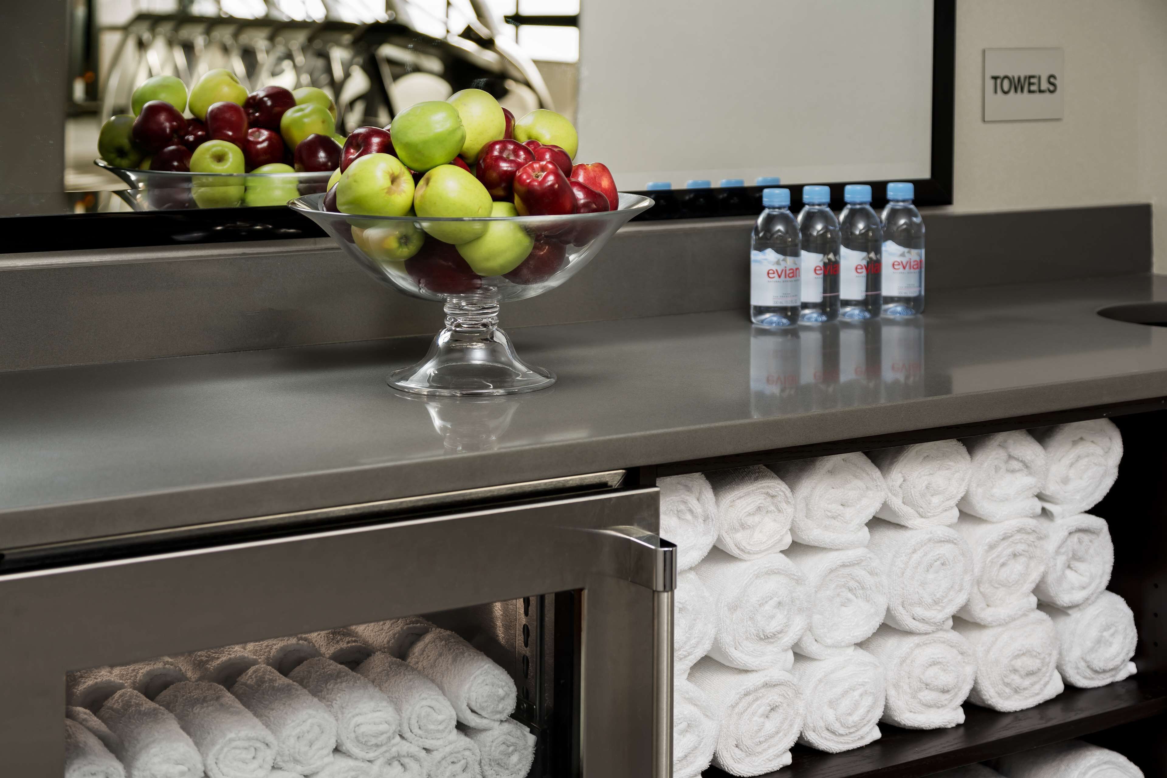 Zona de recepción de un hotel con un frutero, agua embotellada y toallas ordenadamente dobladas.