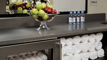 Zona de recepción de un hotel con un frutero, agua embotellada y toallas ordenadamente dobladas.
