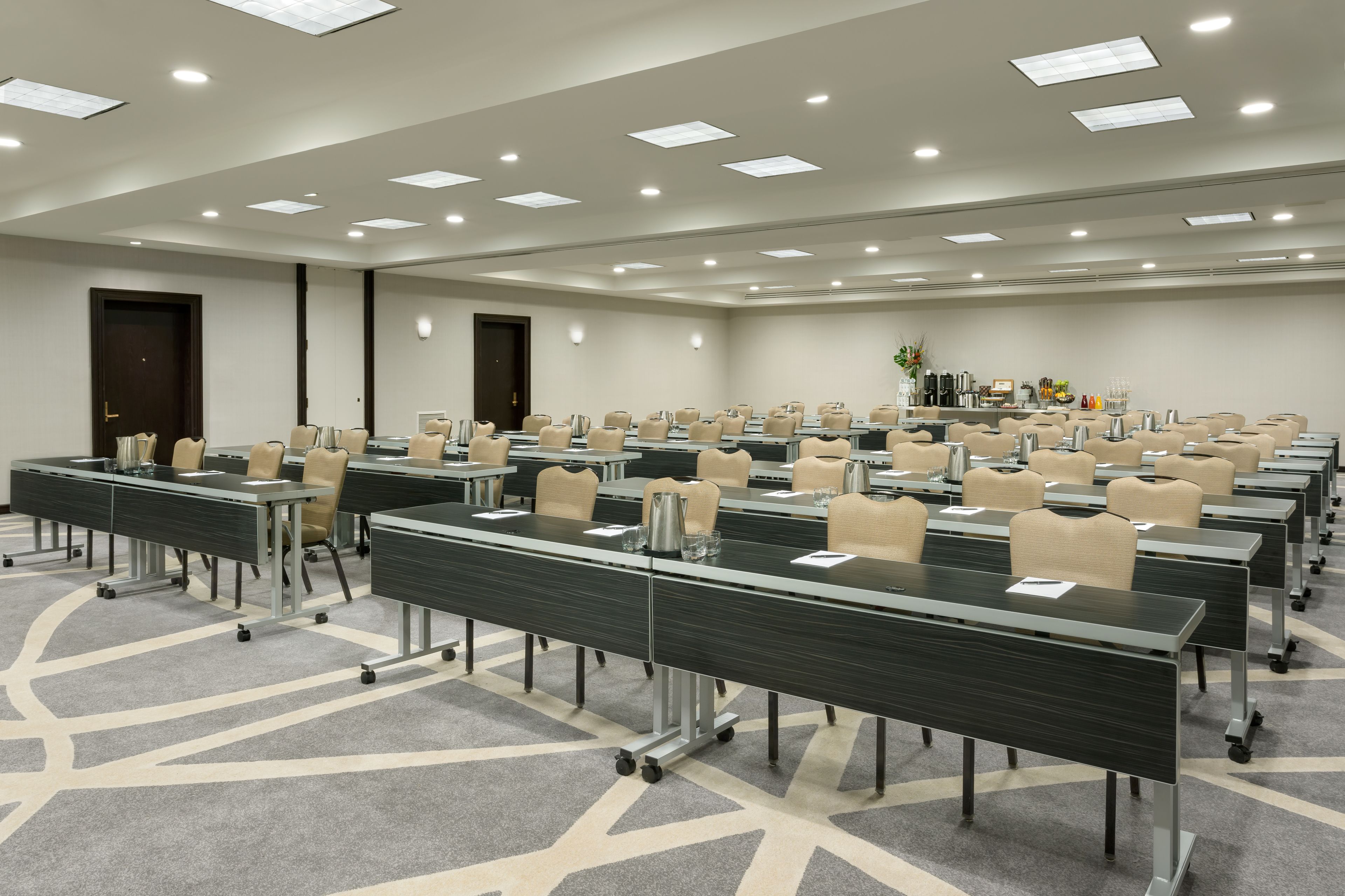 Une salle de conférence dotée de plusieurs tables et chaises, ainsi que de plaques nominatives et de carafes d’eau.