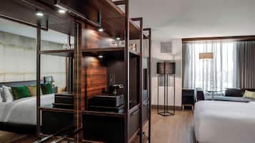 Une chambre d’hôtel moderne avec un grand lit, un bureau avec un ordinateur, une armoire et un miroir.
