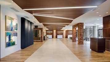 Un moderno vestíbulo de hotel con suelo de madera, un mostrador de recepción y arte abstracto en las paredes.