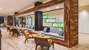 A modern lounge area with a long sofa, cushioned chairs, and a wooden accent wall with artwork. - North Charleston Marriott (North Charleston)