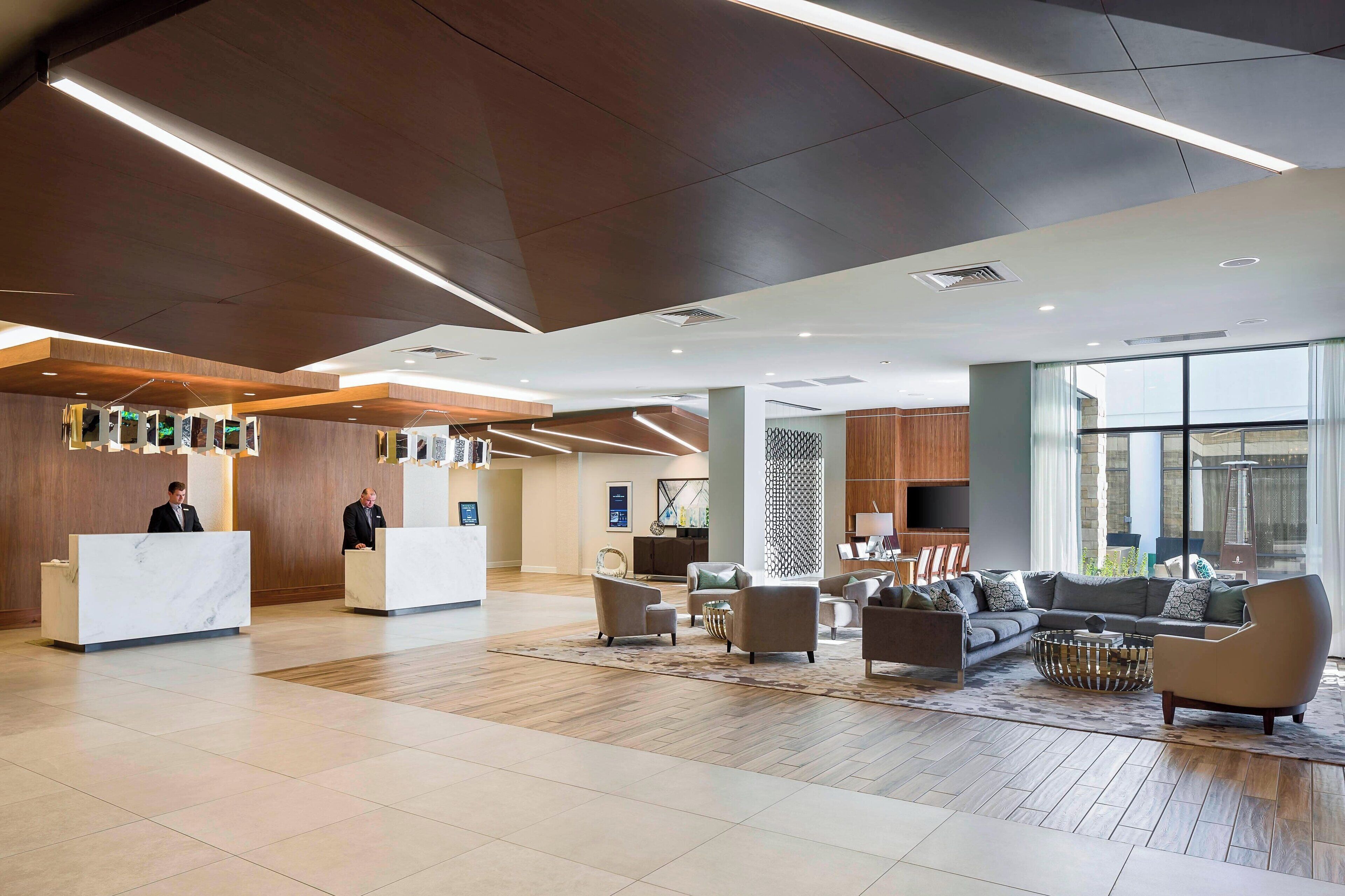 A spacious lobby with a reception desk, seating area, and large windows.