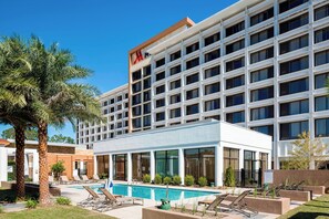 A hotel with a modern design, featuring a pool area with lounge chairs and a clear view of the pool. - North Charleston Marriott (North Charleston)