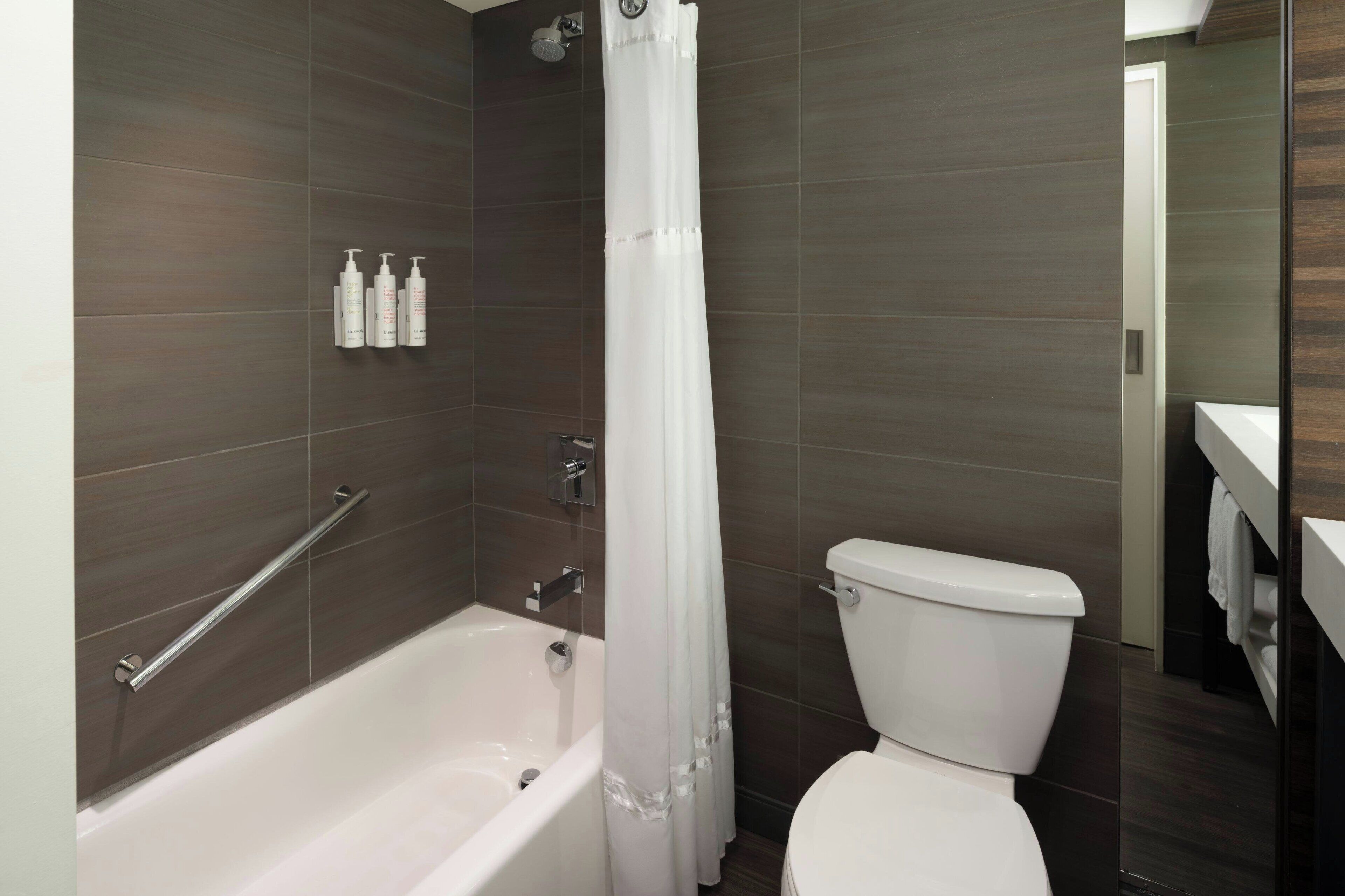 A modern bathroom with a bathtub, shower, and toilet.