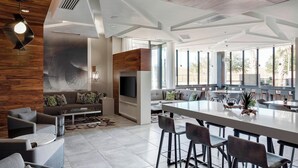A spacious living area with a large sofa, a coffee table, and a dining area with high stools. - North Charleston Marriott (North Charleston)