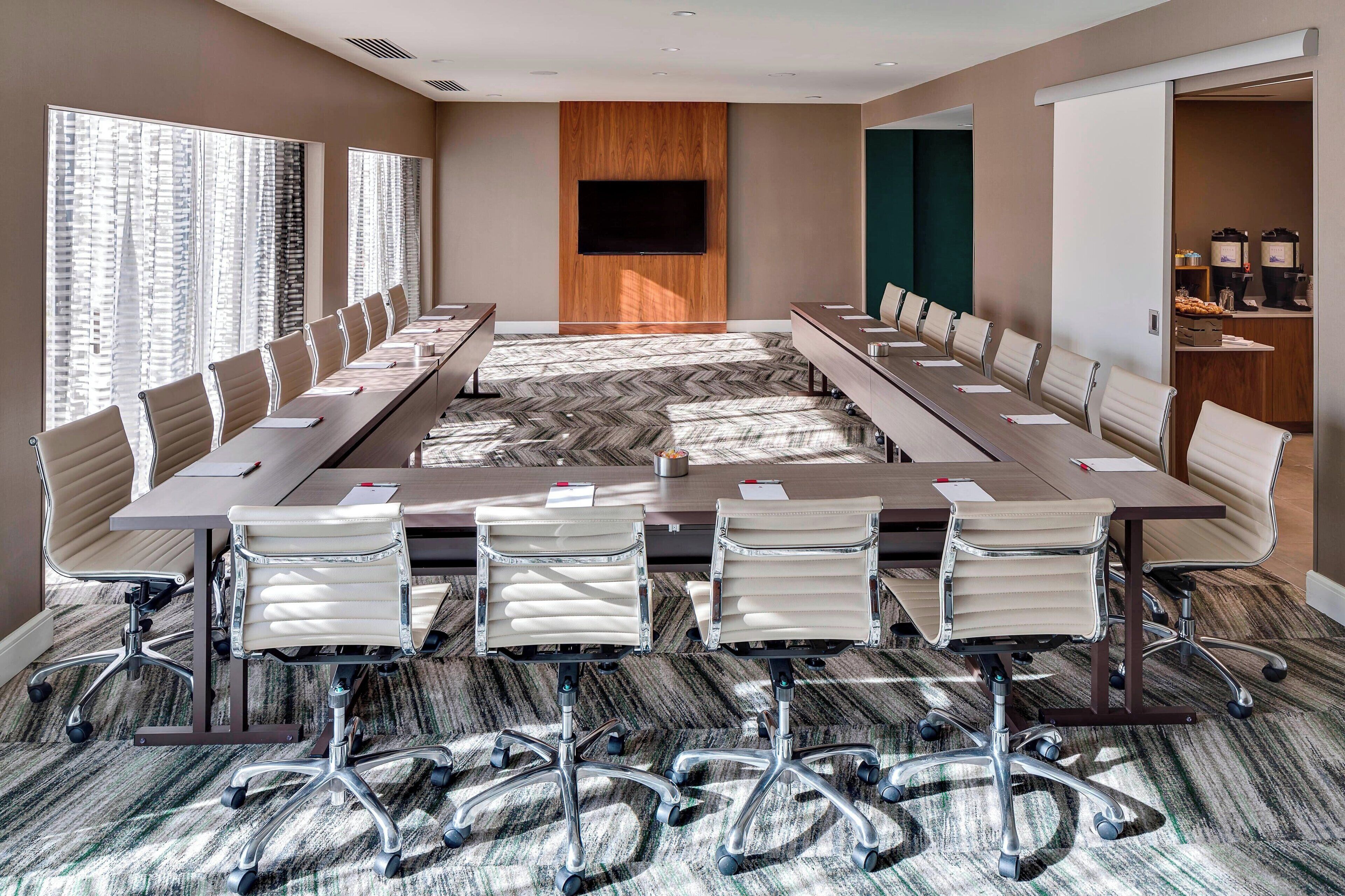 Une salle de conférence équipée d’une longue table, de nombreuses chaises, d’un téléviseur à écran plat et d’un coin café.